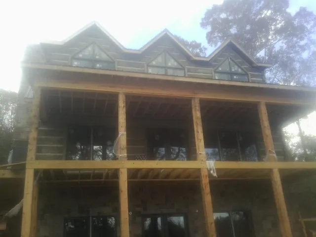 Dormers and porch framing on a large log home under construction — Roof Coating work by our crew in Neptune Beach