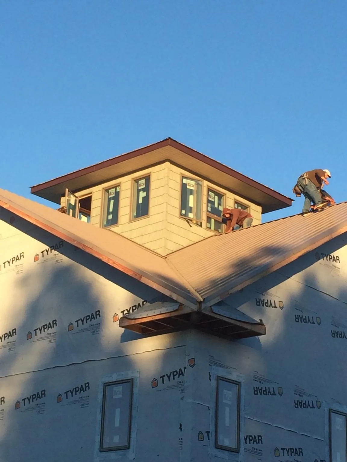 Roofers working around a rooftop cupola on a new metal roof at sunset — Roof Waterproofing in Neptune Beach by Roofing Brothers